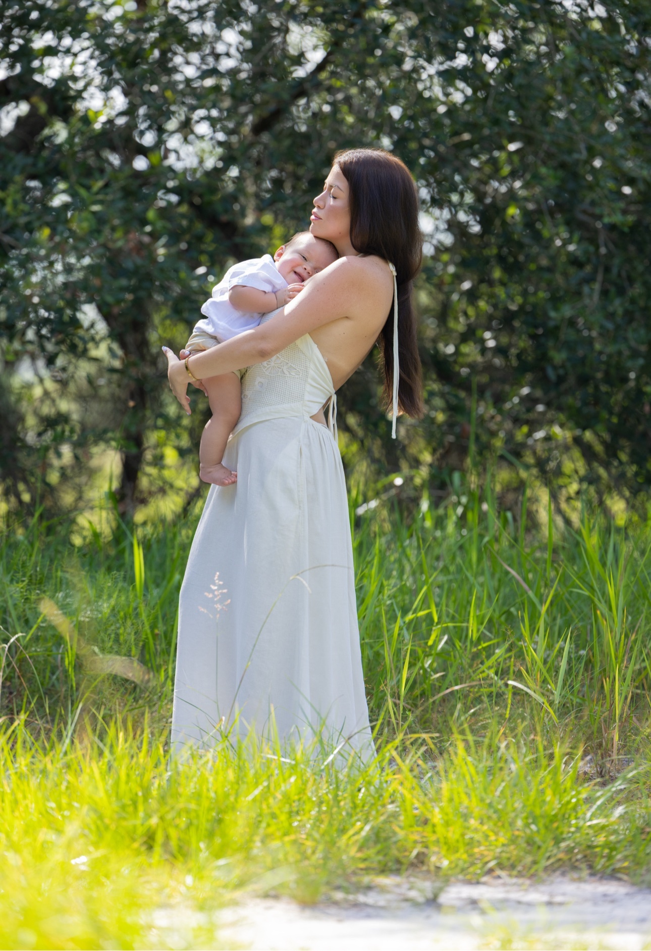 Mother holding her baby in a sunlit green field